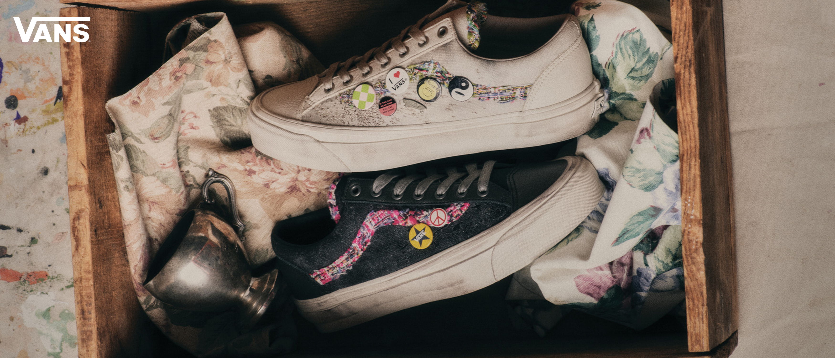 Box containing decorated Vans sneakers and crumpled paper.