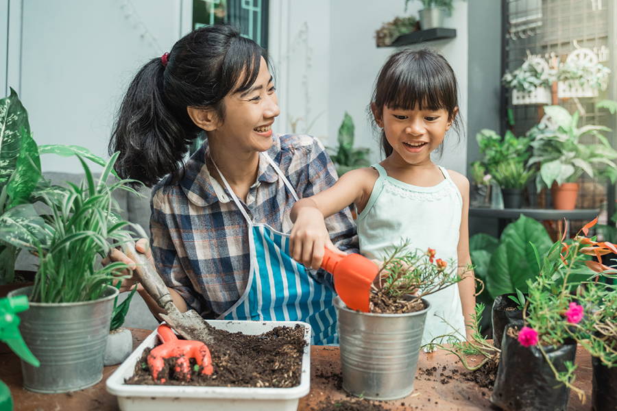 woman and little girl smiling and working on potting plants together