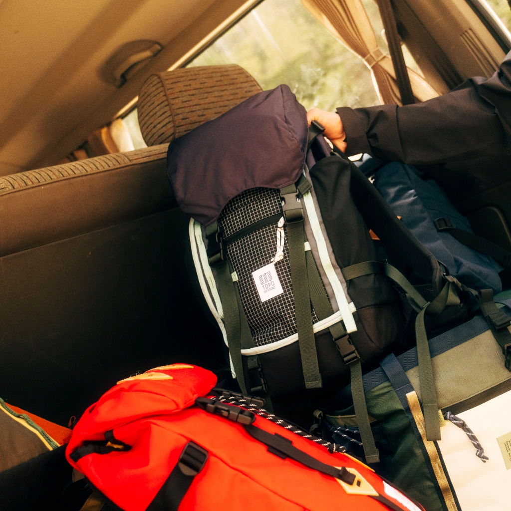Interior of a car with backpacks and gear in the backseat.