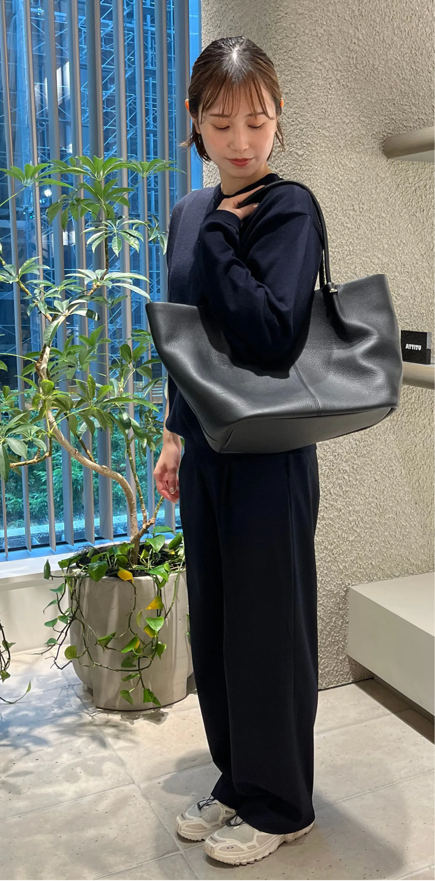 Person in black outfit holding a bag in a store with shelves.