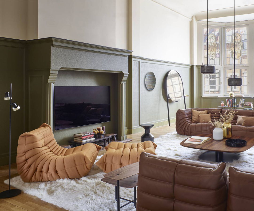 Modern Ligne Roset Togo sofa living room with brown furniture and green walls.