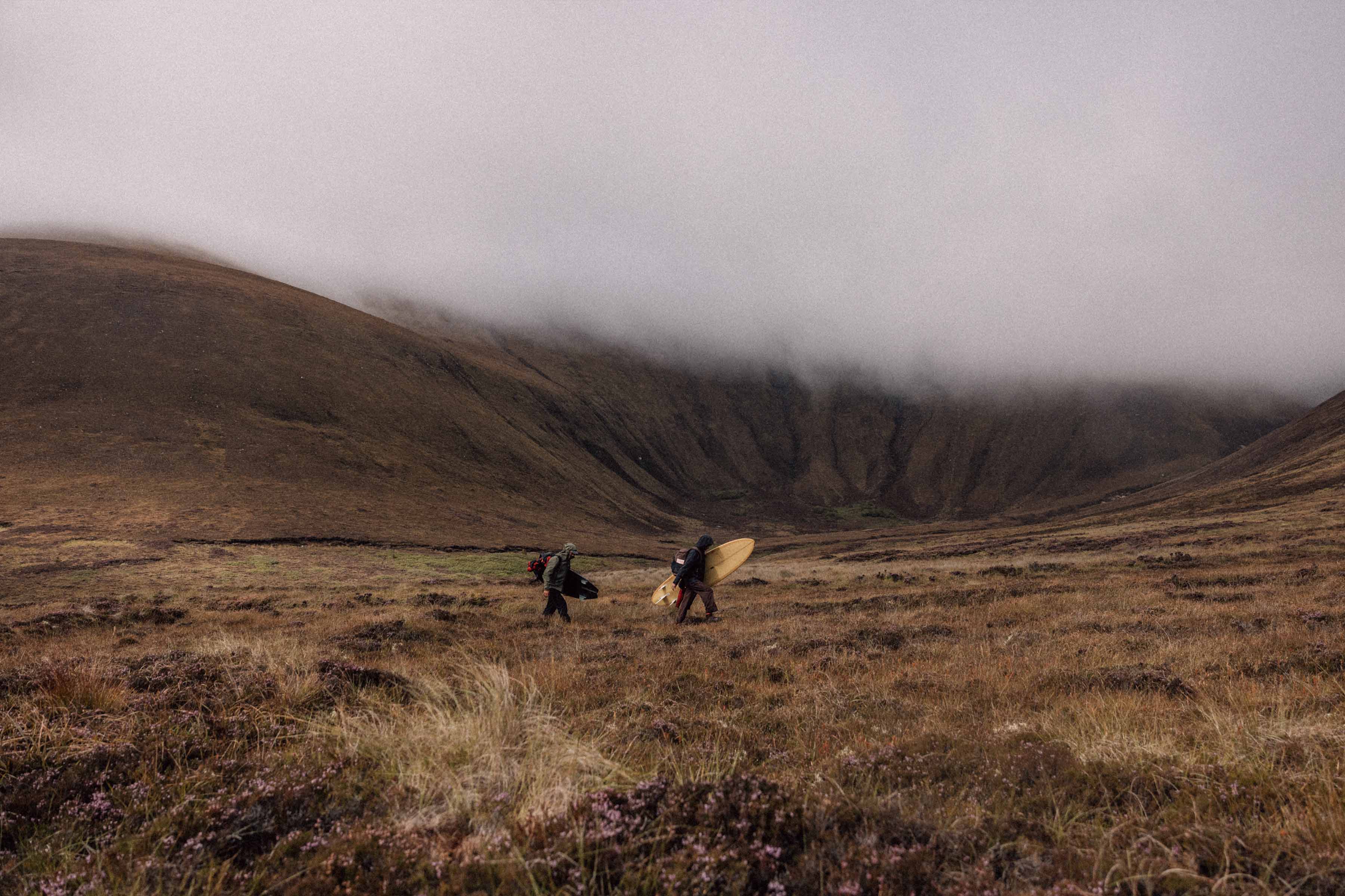 Two people walking in a misty, mountainous landscape.