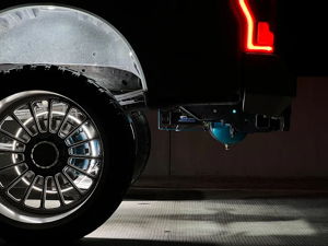 Close-up of Holden's Ford F250 rear wheel at night with LED ring lights and teal air tank