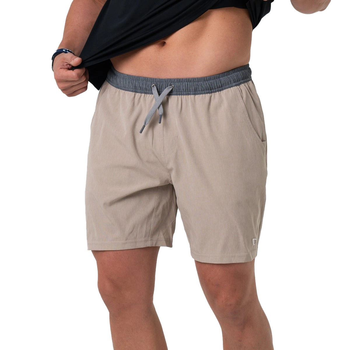 A person wearing beige shorts and lifting a black shirt.