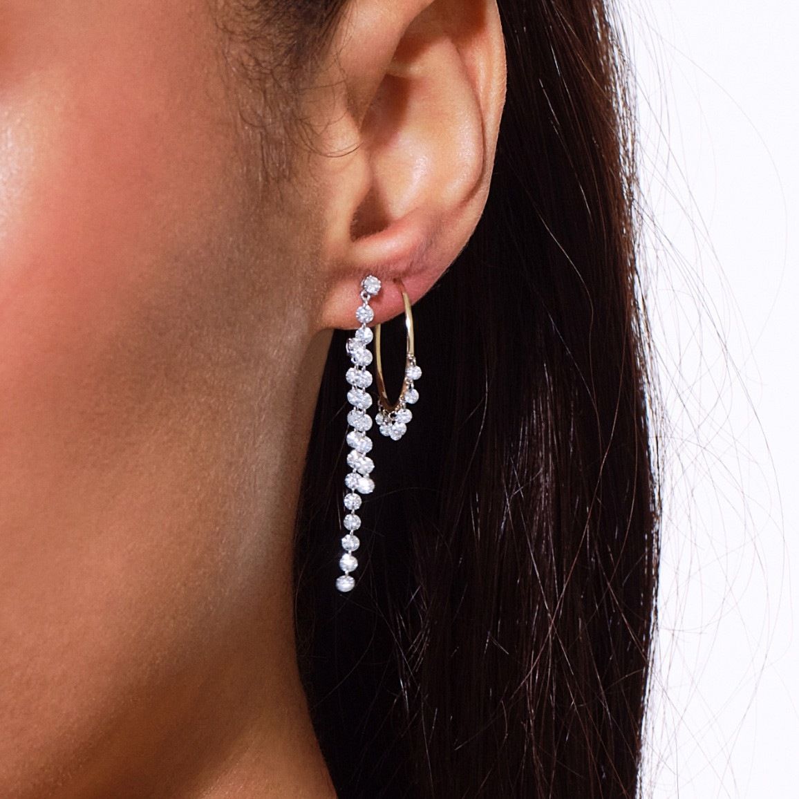 Close-up of a woman's ear wearing a long, dangling pearl earring.