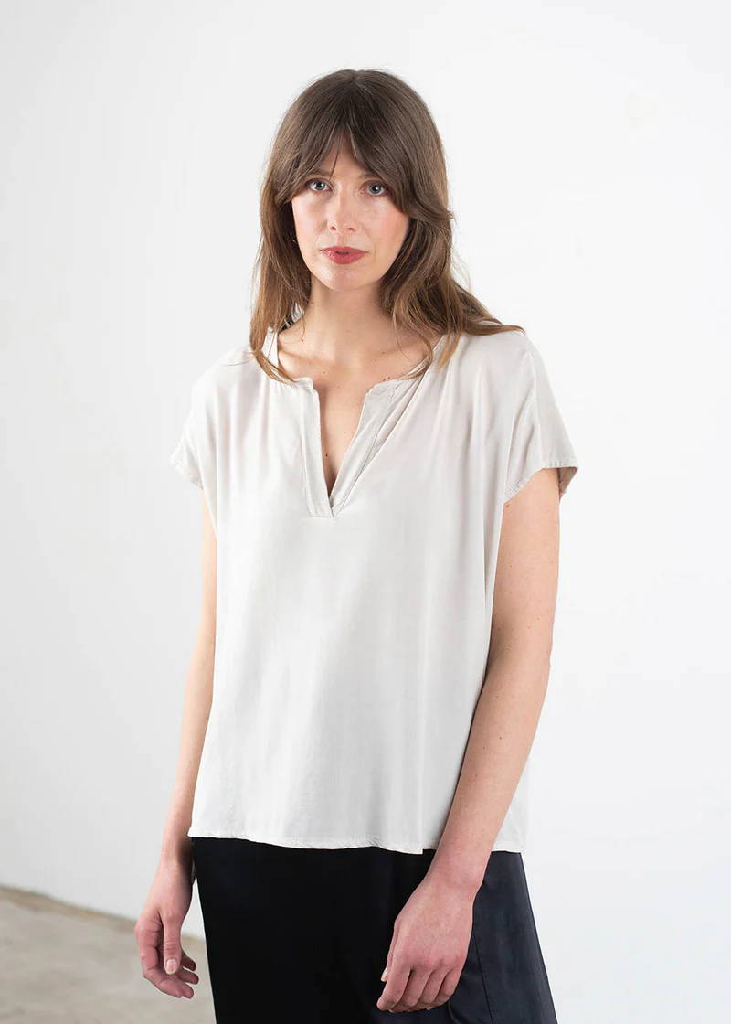 A model wearing an off white, oatmeal coloured short sleeved top with a v-neckline