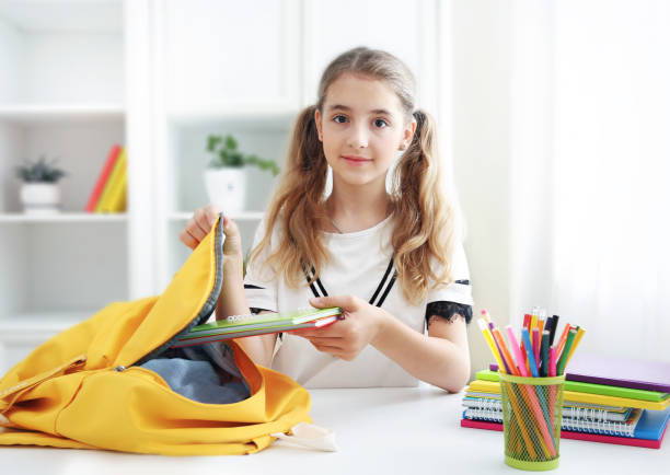 female student putting books into backpack