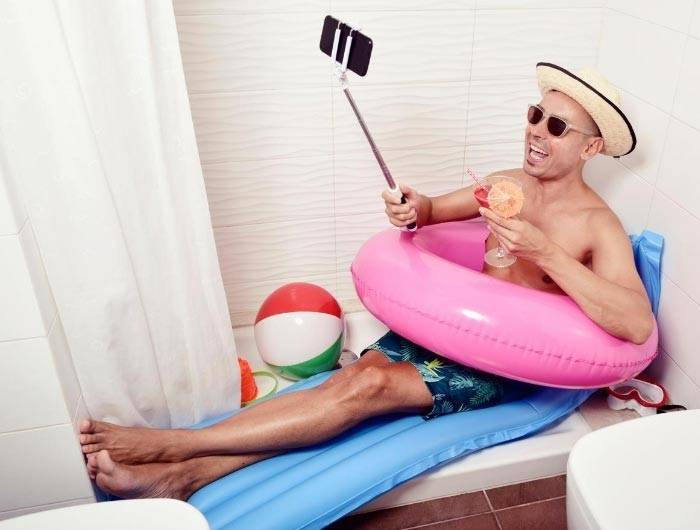 Man in bathtub wearing bathing suit pretending to be on vacation