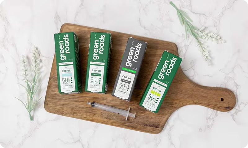 Four green product boxes and a syringe on a wooden cutting board.
