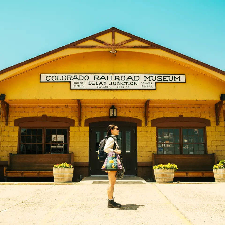 Woman standing in front of the Colorado Railroad Museum building on a sunny day.