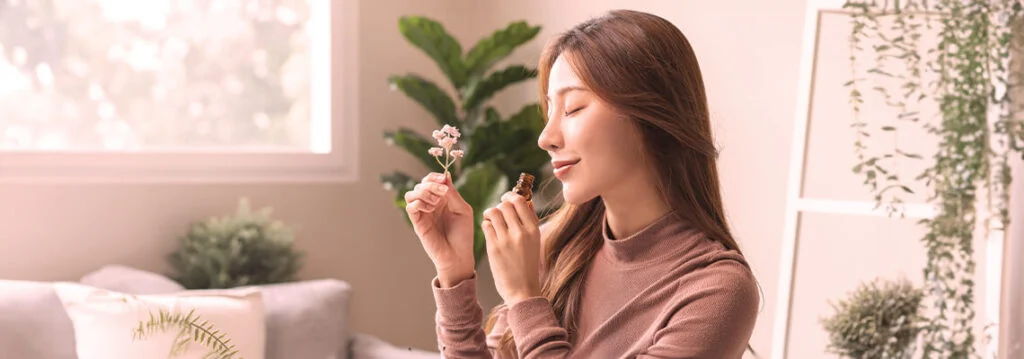 A woman smiling while holding a small object in a bright, indoor setting.