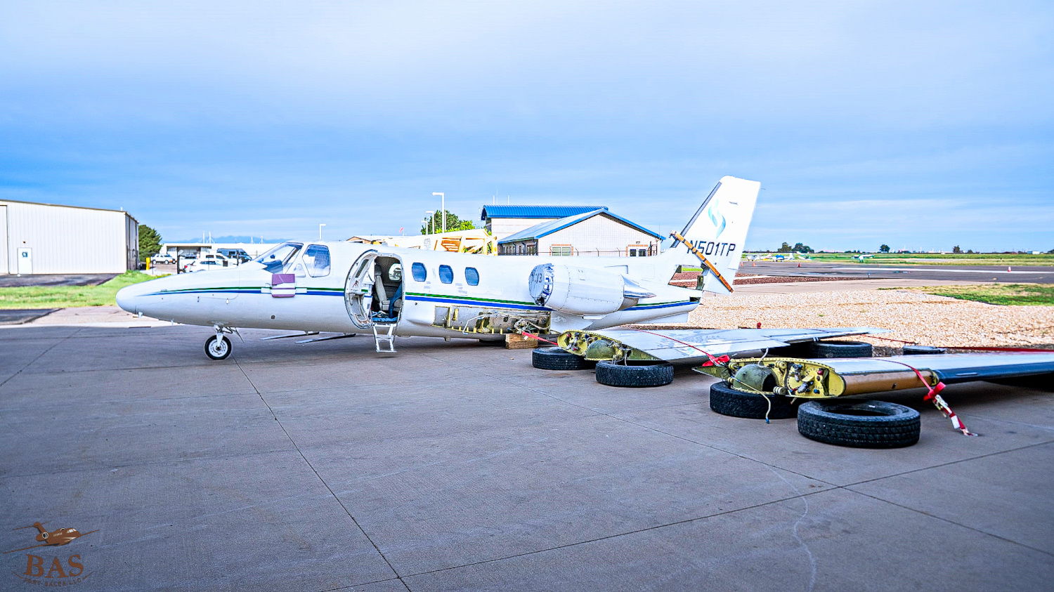 Private jet parked at an airport with a cloudy sky.