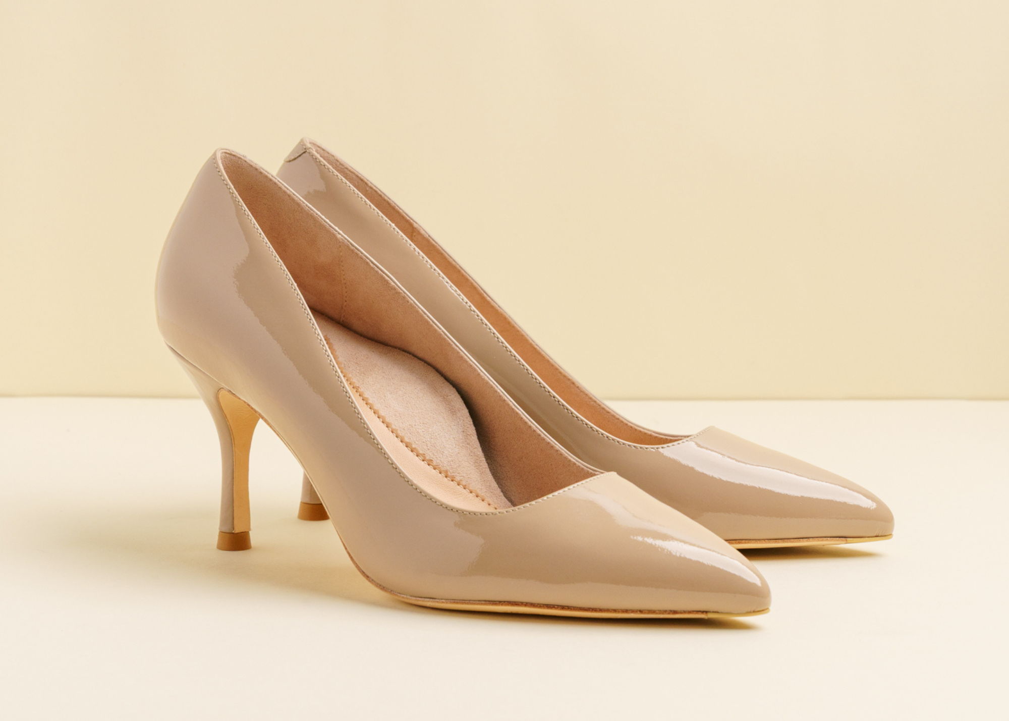 A beige high-heeled shoe on a neutral background.