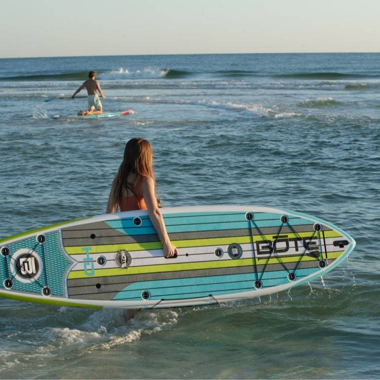Woman carrying her HD Full Trax Citron Paddle Board into the surf