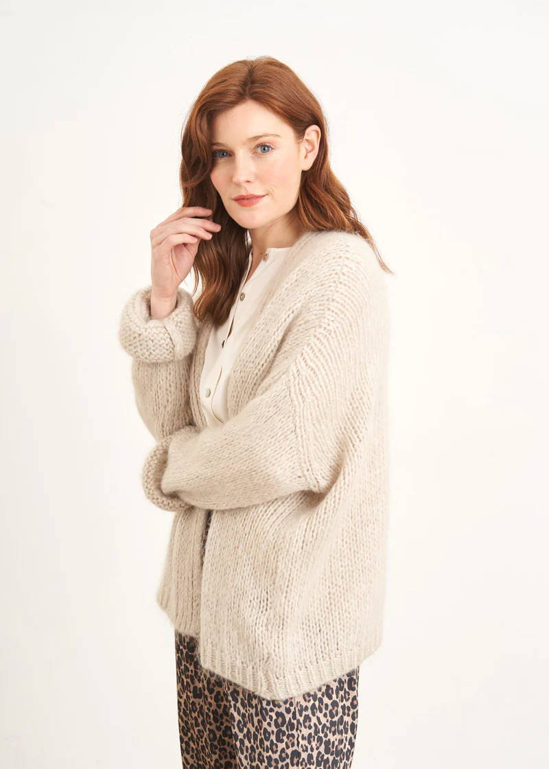 A model wearing an off white chunky knit cardigan