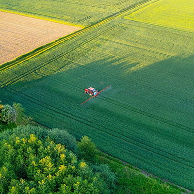 Aerial view of a field being sprayed by agricultural machinery.