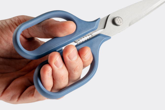 A close view of a hand holding Blue Misen Kitchen Shears’ ergonomic handles.