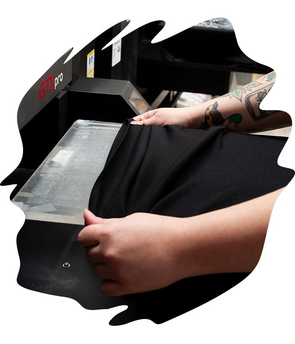Hands positioning black garment onto DTG printer platen ready for high-resolution print application.
