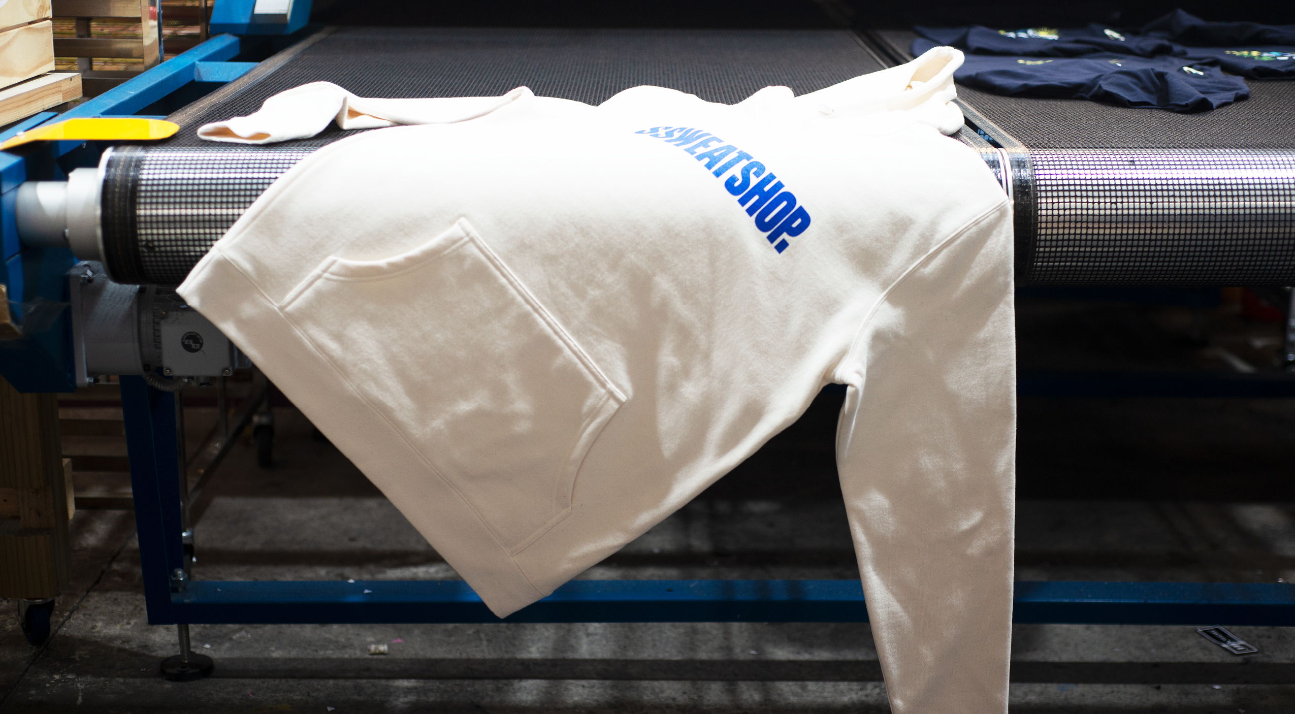 A white garment with blue text draped over a conveyor belt.