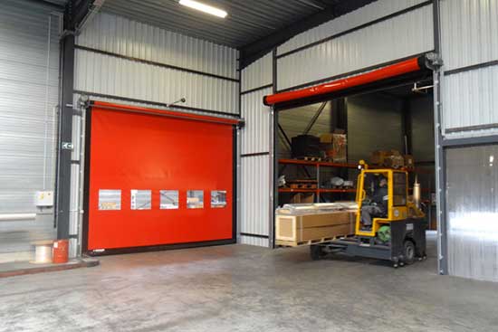 Warehouse interior with red door and forklift loading materials.