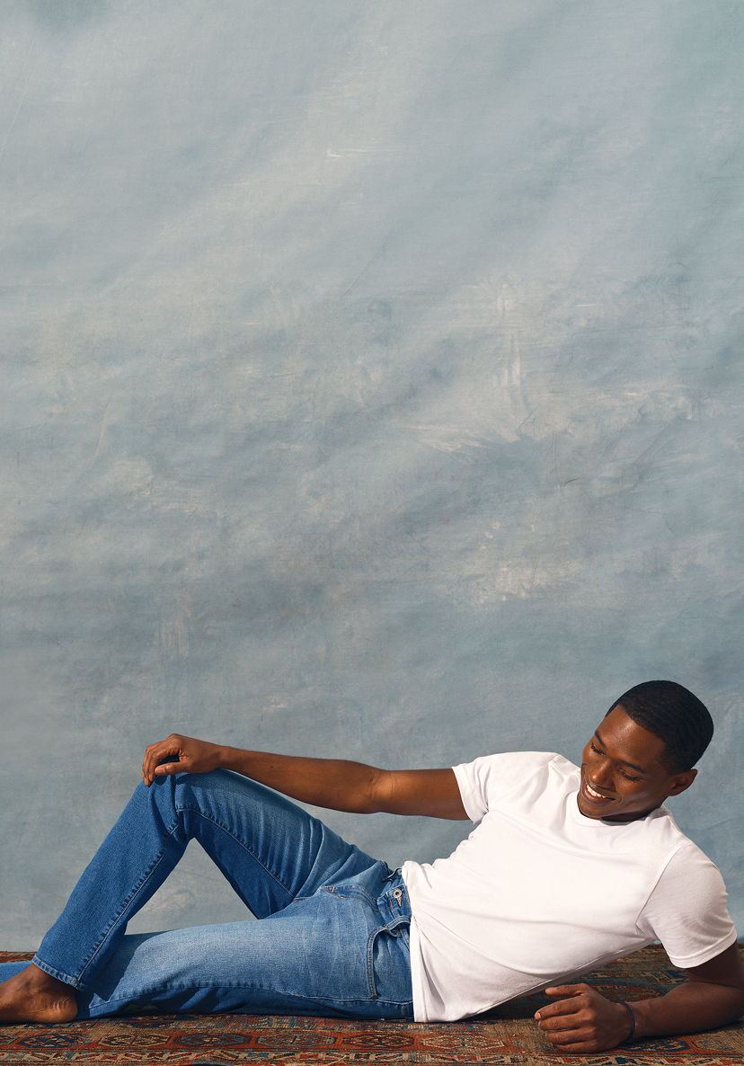 A person lying on a rug against a blue background.