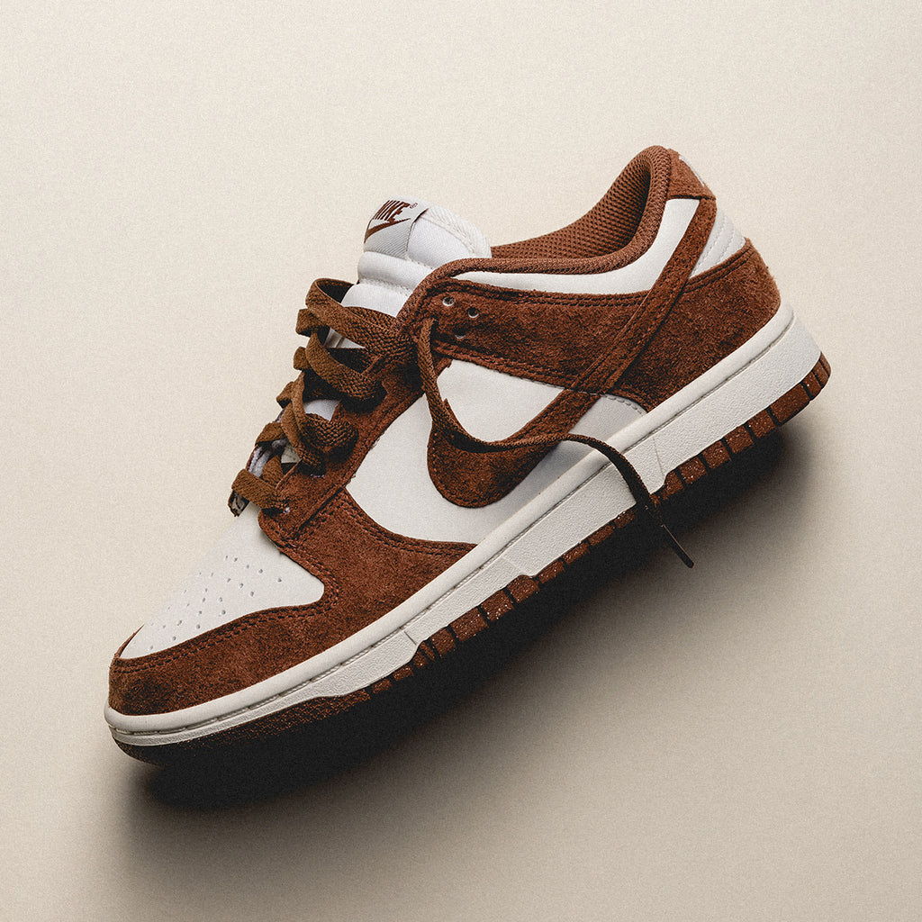 Brown and white Nike sneaker on a neutral background.