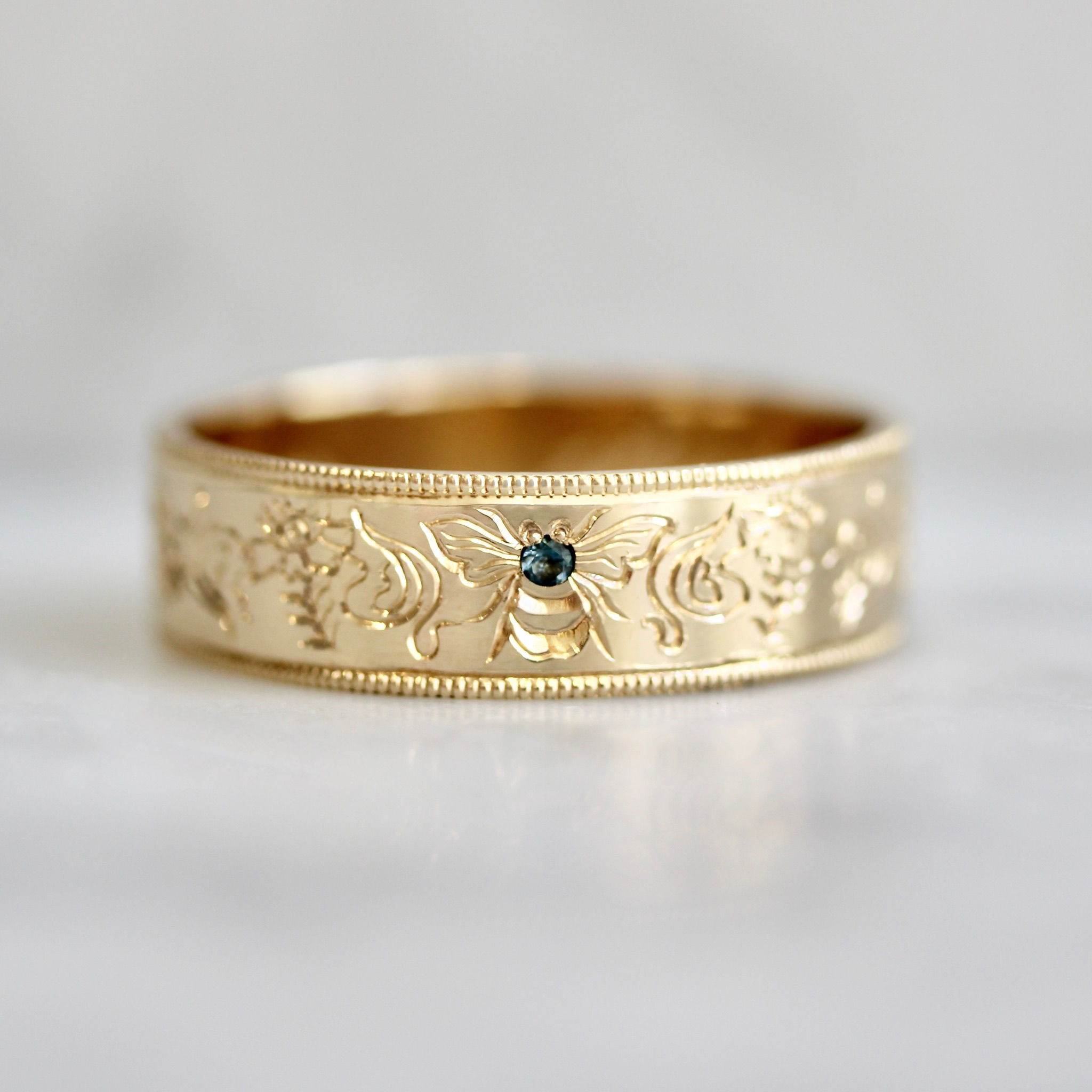 Hand-engraved bee wedding band with sapphire