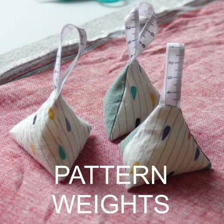 Three triangle home-made pattern weights on a piece of fabric