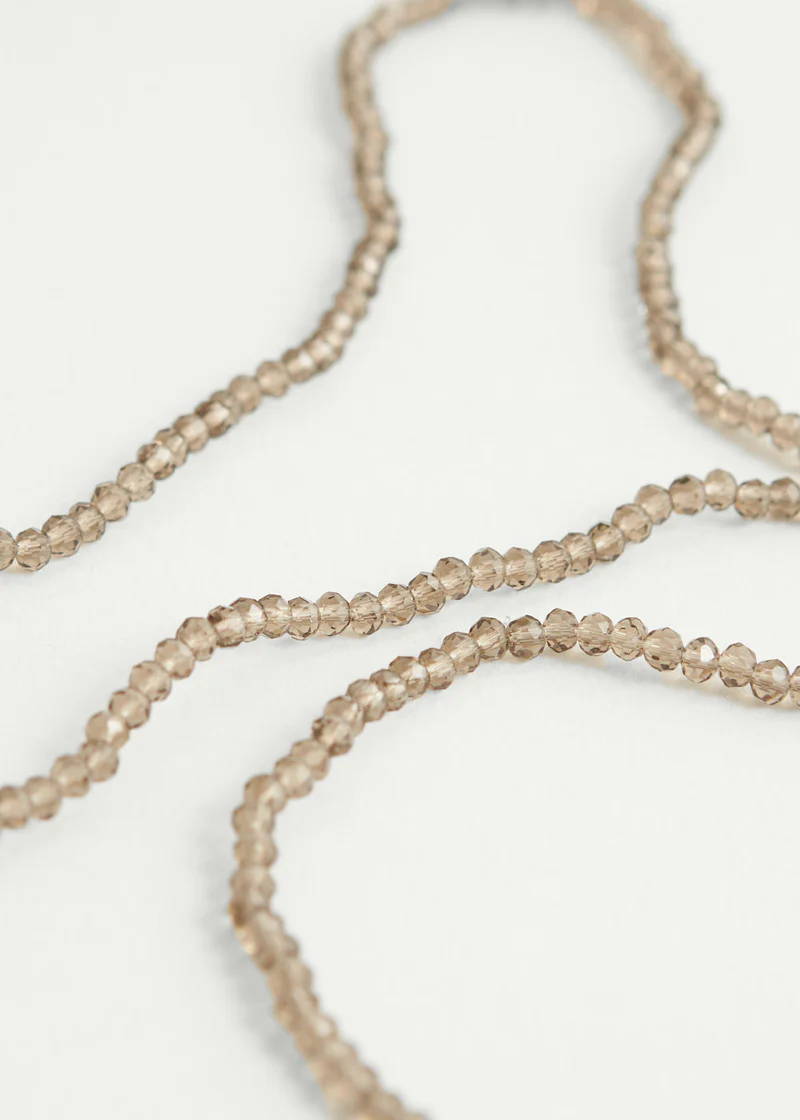 A long necklace comprised of small cleae brown crystal beads