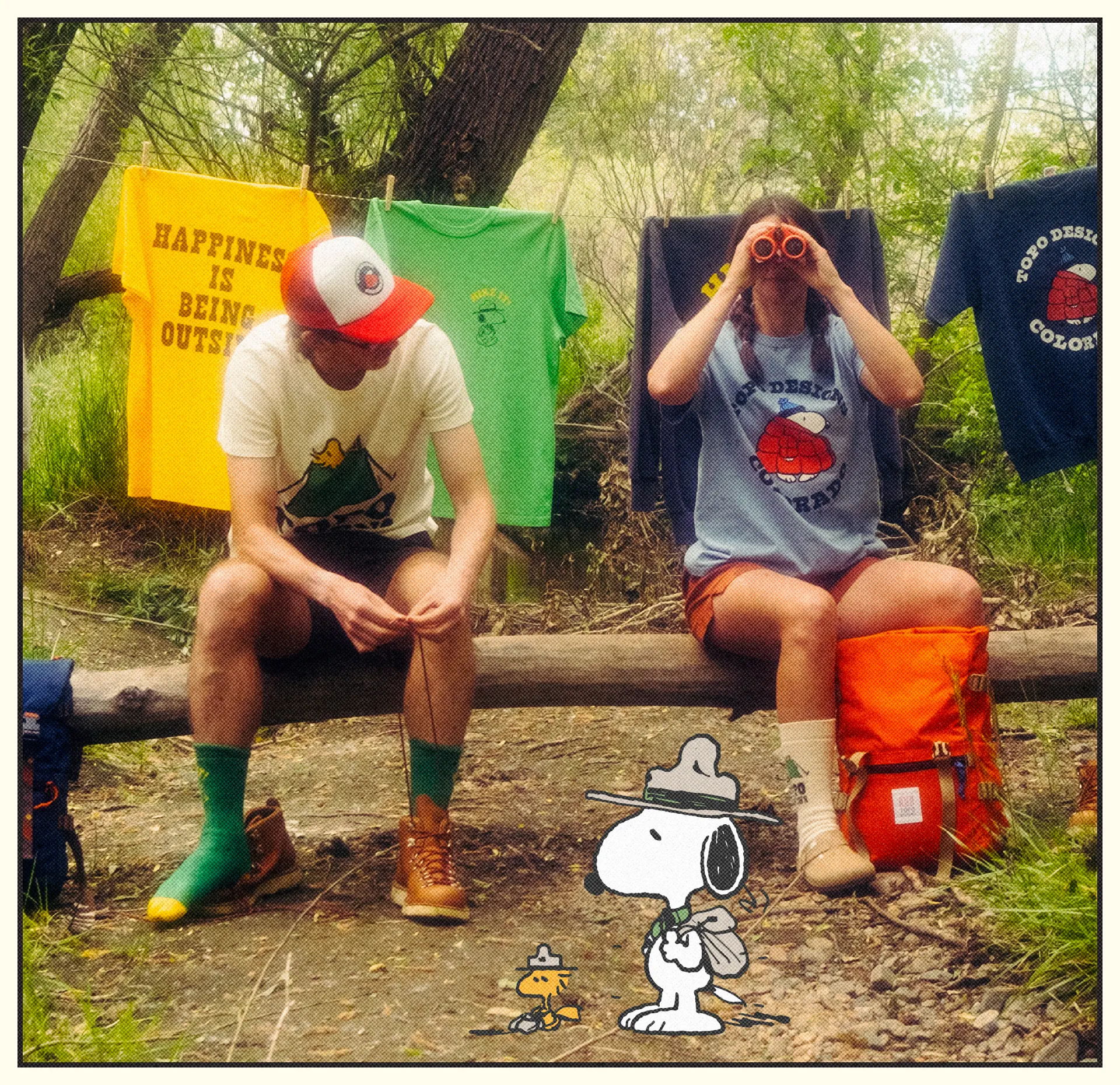 Two hikers resting by a stream with Snoopy cartoon character.