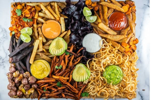 A colorful potato recipe platter with various dips and snacks arranged artistically.