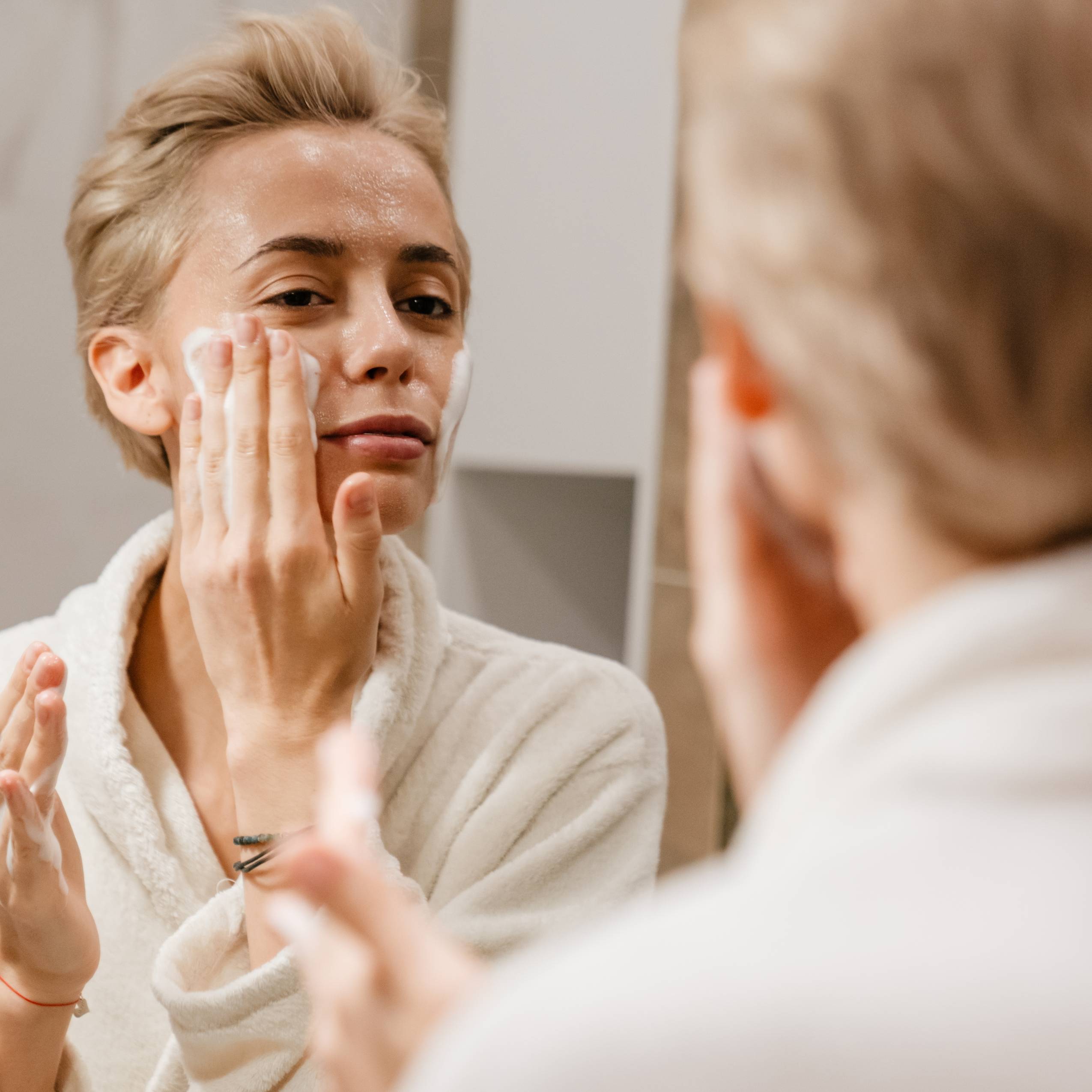 Woman applying cleanser to face 
