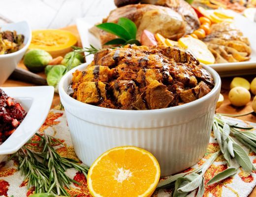 A bowl of bread pudding surrounded by various fruits and dishes.