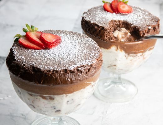 Two dessert bowls with chocolate mousse, whipped cream, and strawberries on top.
