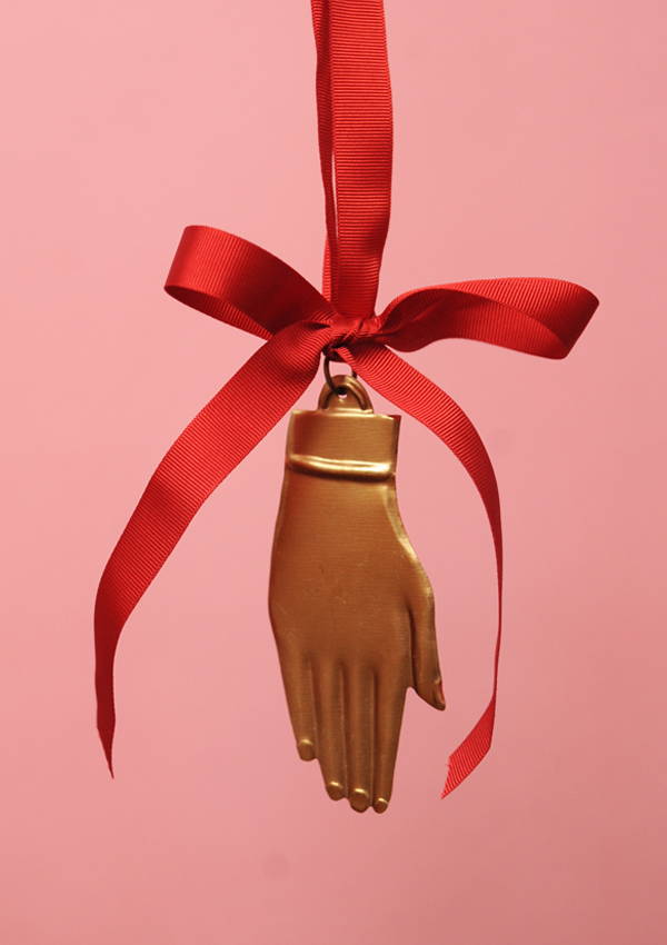 A flat brass hand decoration hung with a red ribbon.