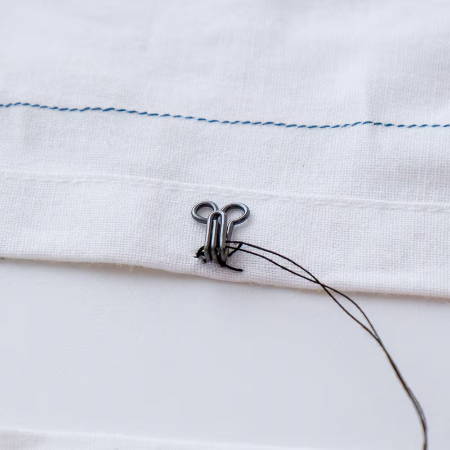 Secure a hook on a garment with black thread