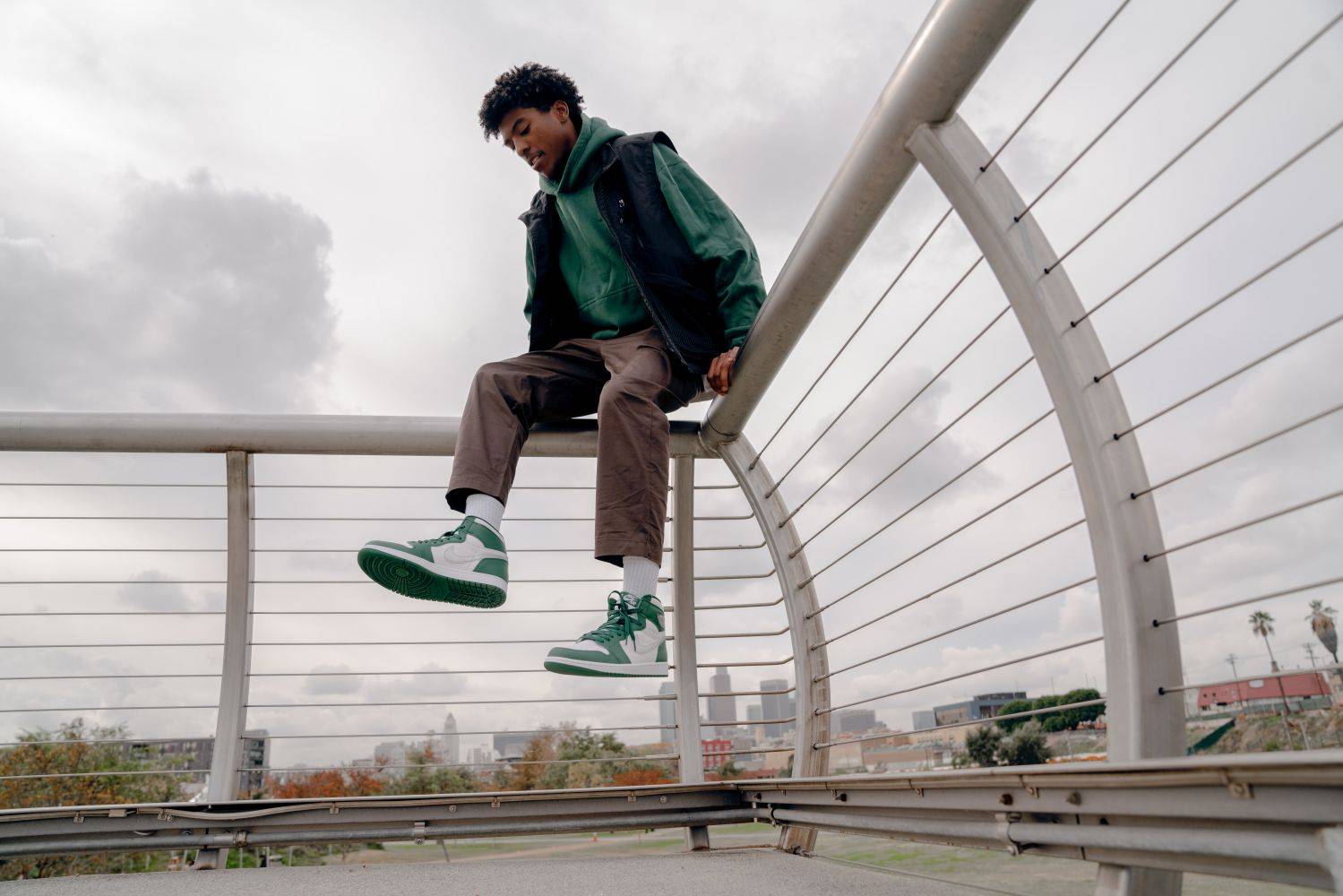 male model in aj1 gorge green jumping of railing