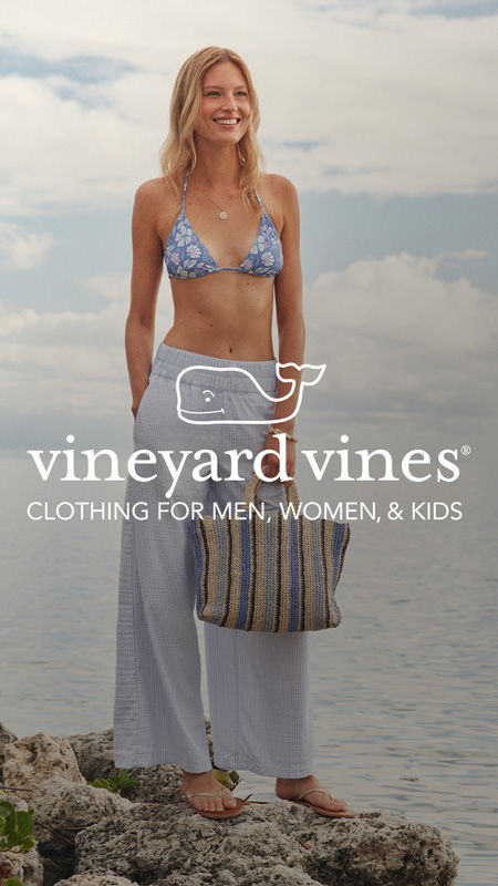 Woman in a bikini and pants, standing by water, showcasing clothing brand.