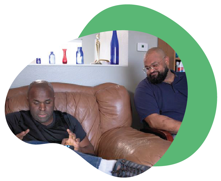 Two men sitting on a couch, engaged in conversation.