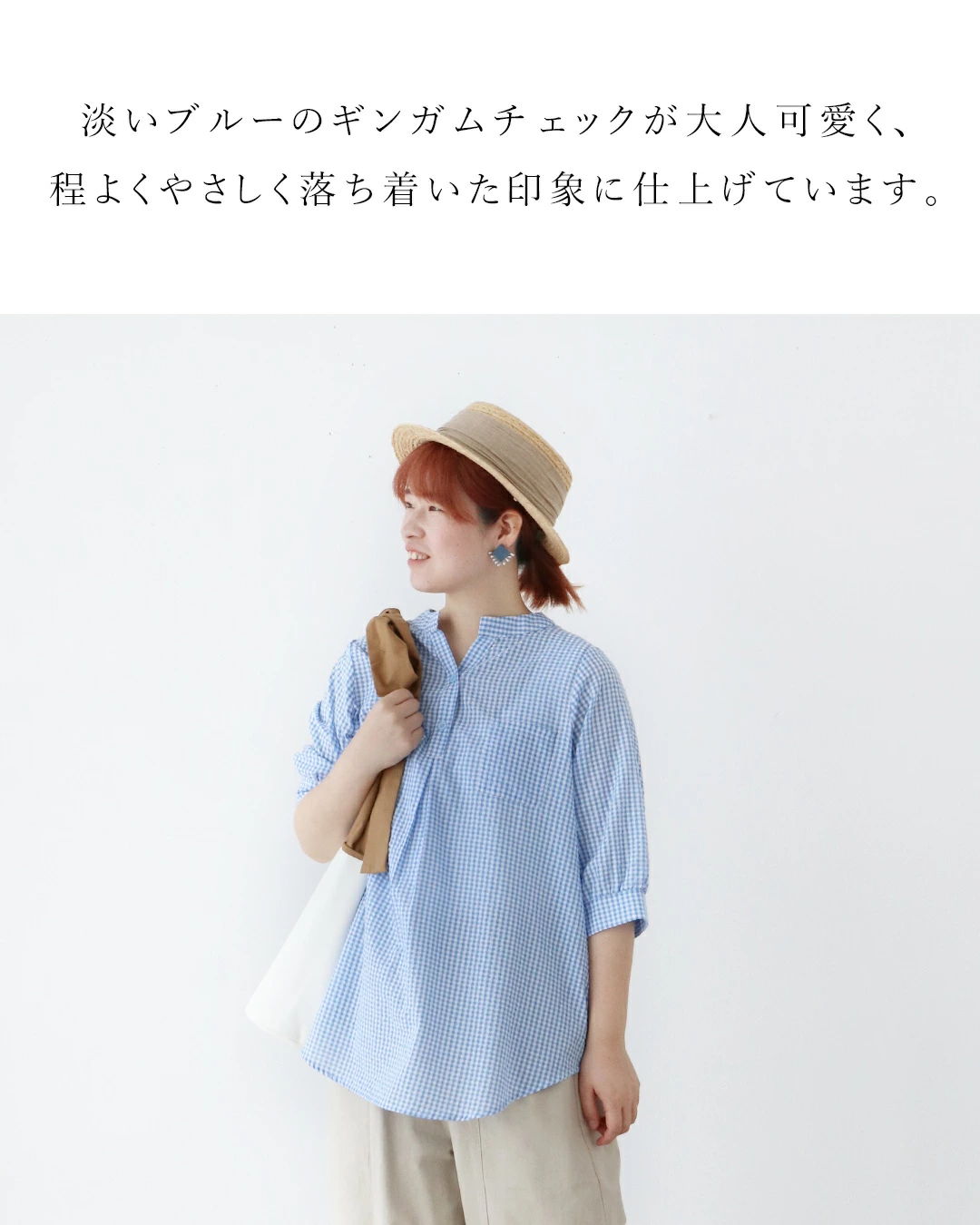 Woman wearing a light blue shirt and a hat, standing against a white background.