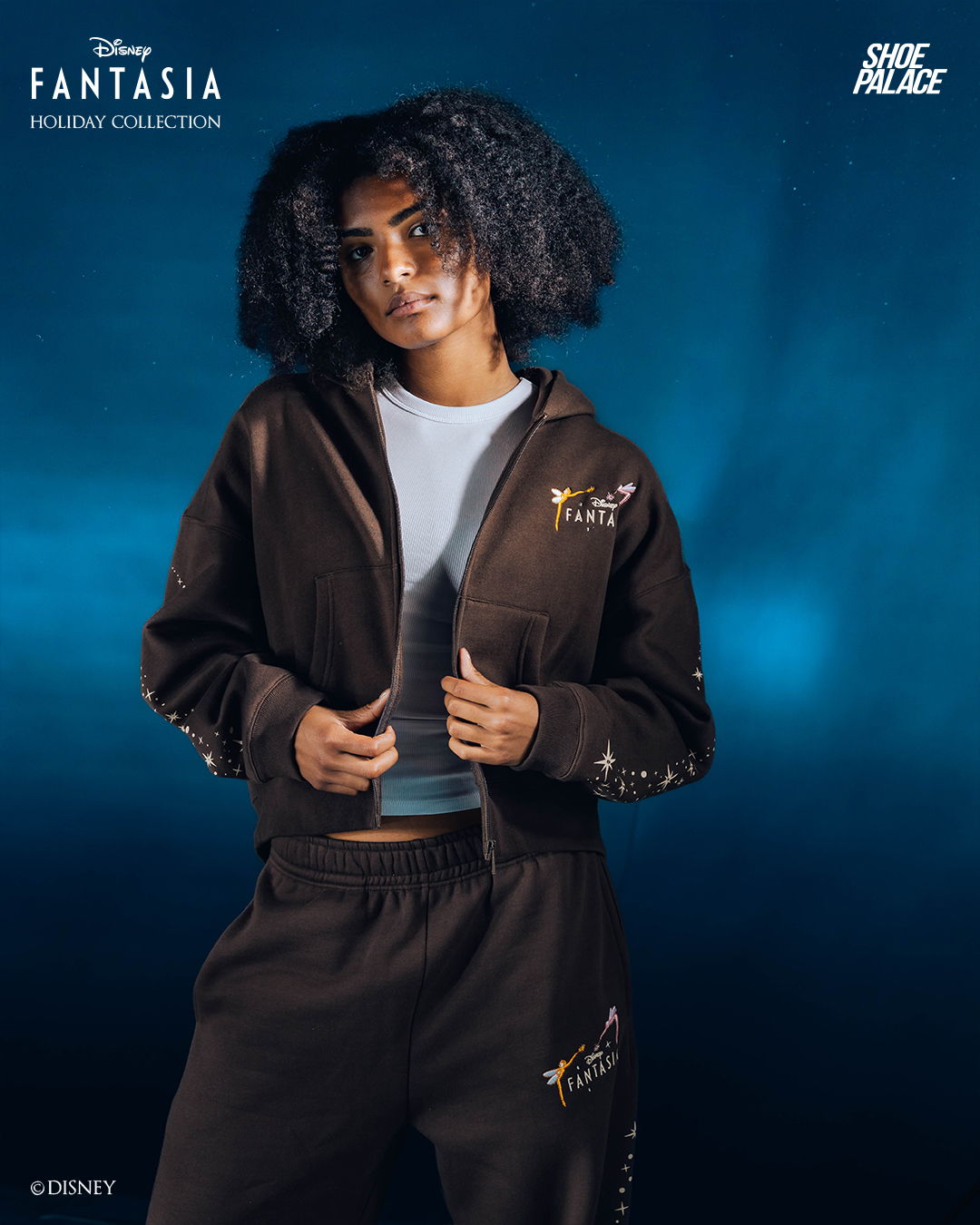 Young woman in stylish Fantasia hoodie and sweatpants against a blue background.