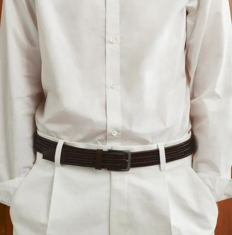 Person wearing a white shirt and beige pants with a brown belt.