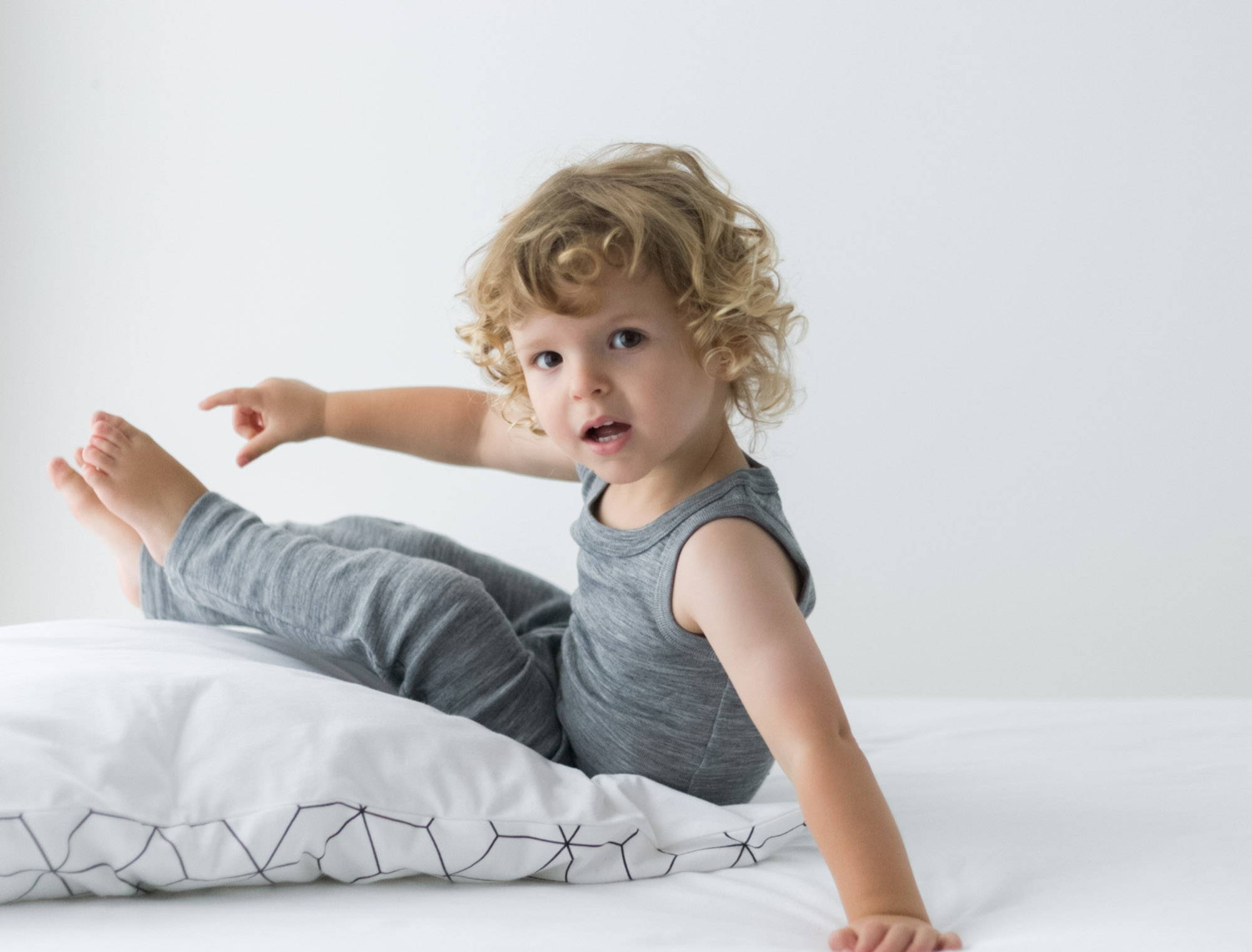boy-toddler-wearing-merino-vest-pyjamas-sitting-on-duvet-and-mattress 