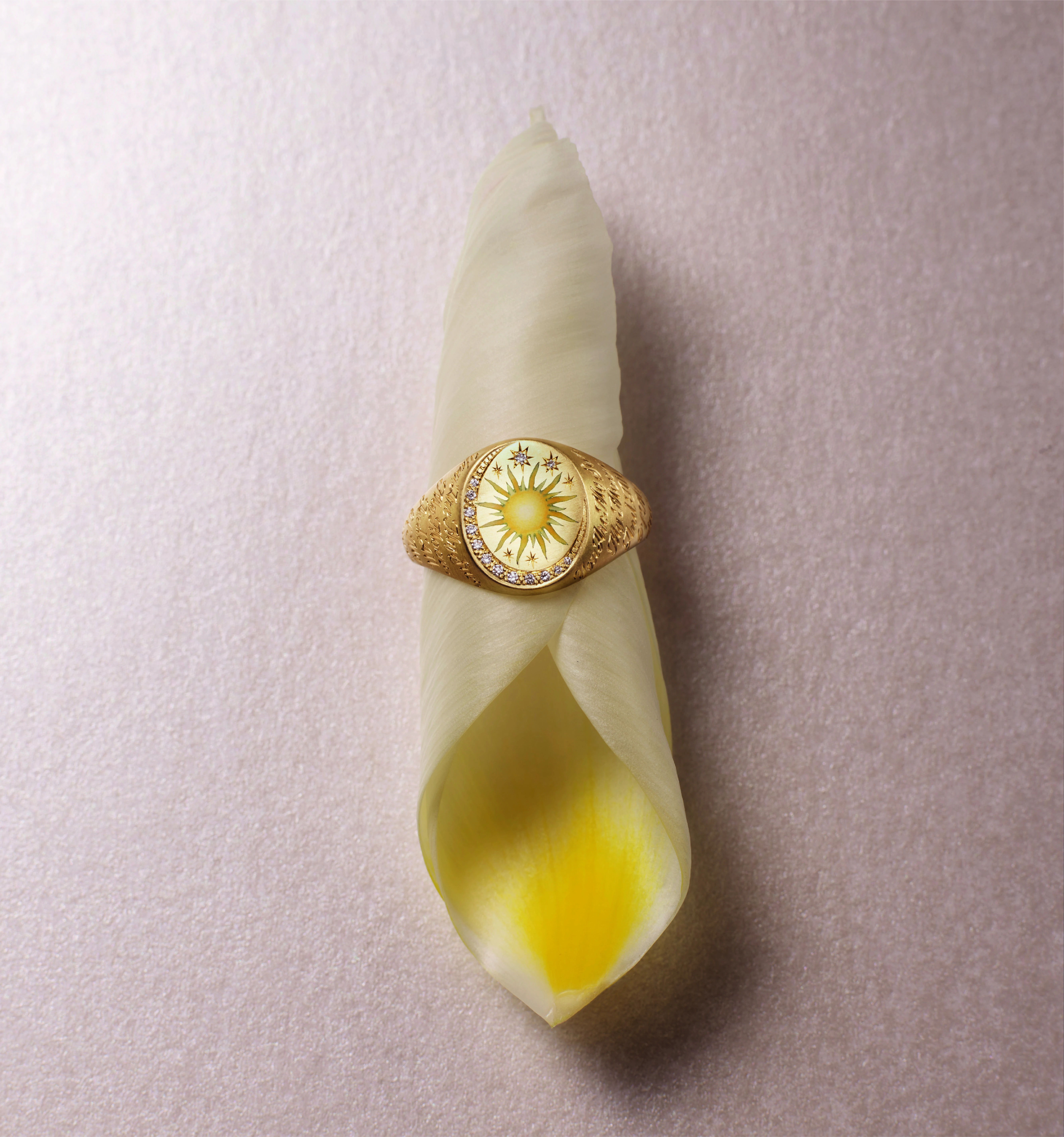 Gold ring with yellow stone on a folded leaf.
