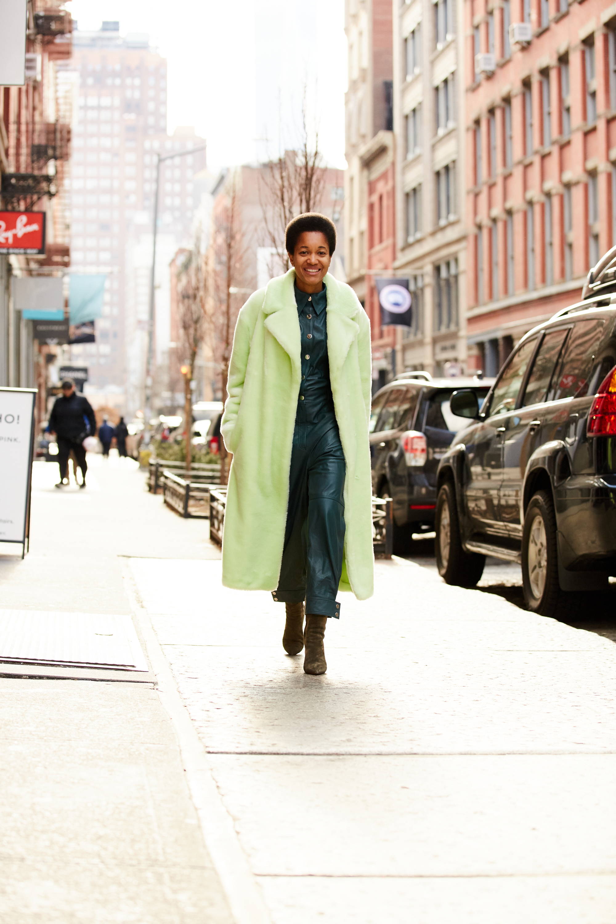 A person wearing a green coat walking down a city street.