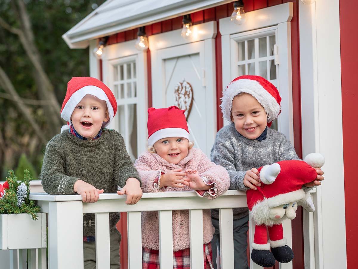 Kids looking for Santa on the fully finished red and white playhouse terrace by WholeWoodPlayhouses