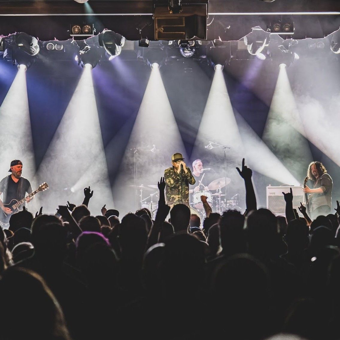 A live music performance with a cheering crowd and dramatic lighting.
