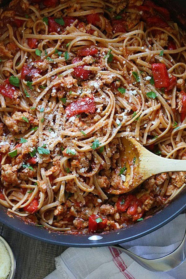 Whole wheat linguine with sausage and peppers in pot with serving spoon