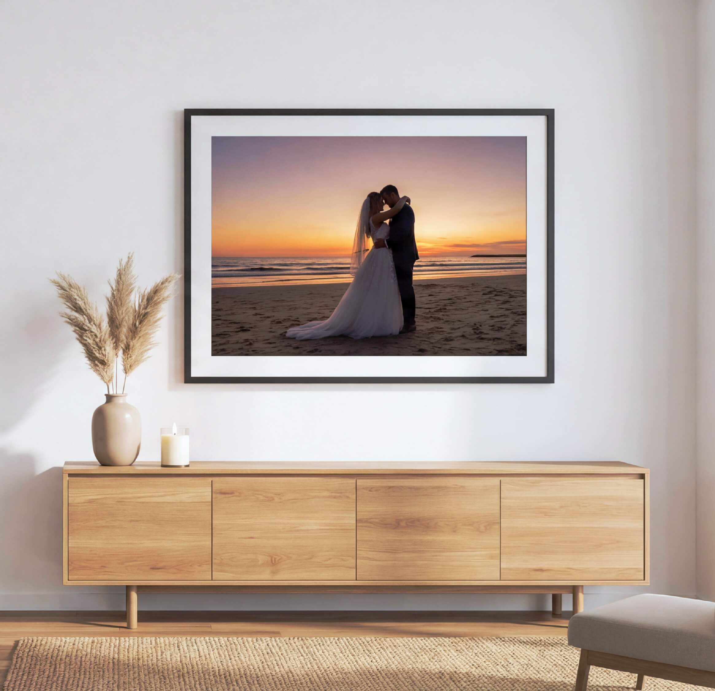 Couple kissing at sunset displayed in a framed photo on a wall.