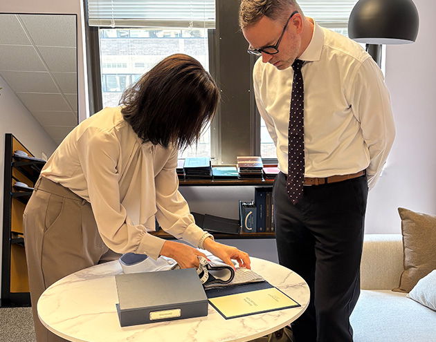 Two people examining documents on a table in an office setting.